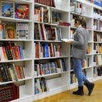 Une jeune femme à la bibliothèque, souffrant du TDAH (trouble déficitaire de l'attention avec hyperactivité), suivant un cursus universitaire dans une grande école.
