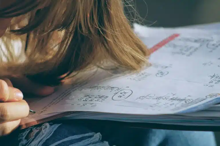 Adolescente penchée sur ses notes de cours, les cheveux devant le visage
