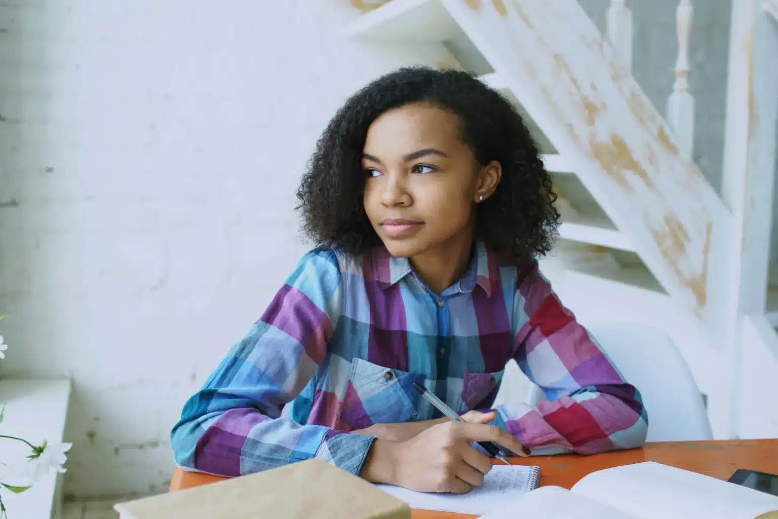 Adolescente pensive assise à son bureau avec ses cahiers