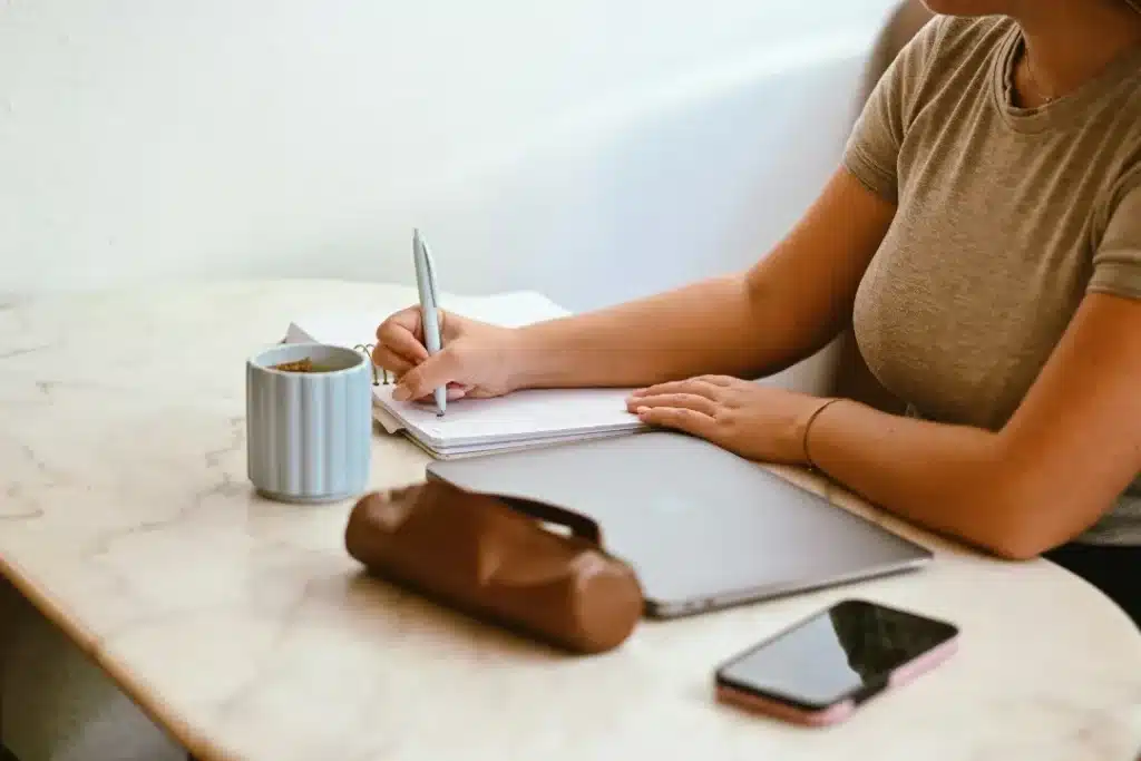 Femme qui écrit dans son agenda sur une table en marbre