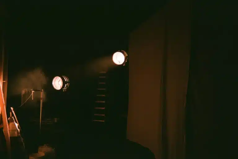 Scène vide éclairée par trois projecteurs avant un spectacle
