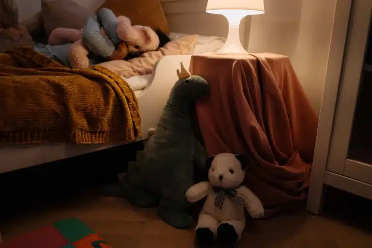 Chambre d'enfant la nuit, veilleuse allumée et peluches au pied du lit