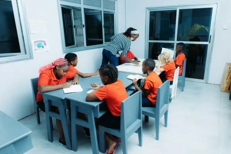 Enseignante qui explique une activité à un petit groupe d’enfants assis autour de tables