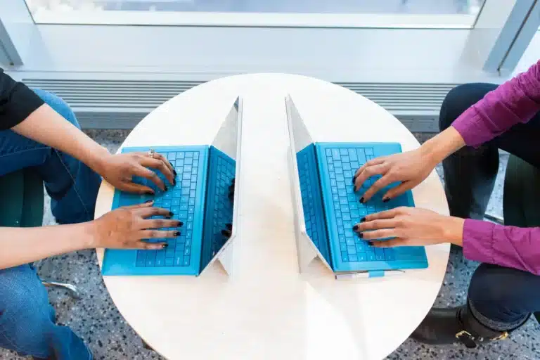 Deux personnes qui travaillent face à face sur leur ordinateur portable
