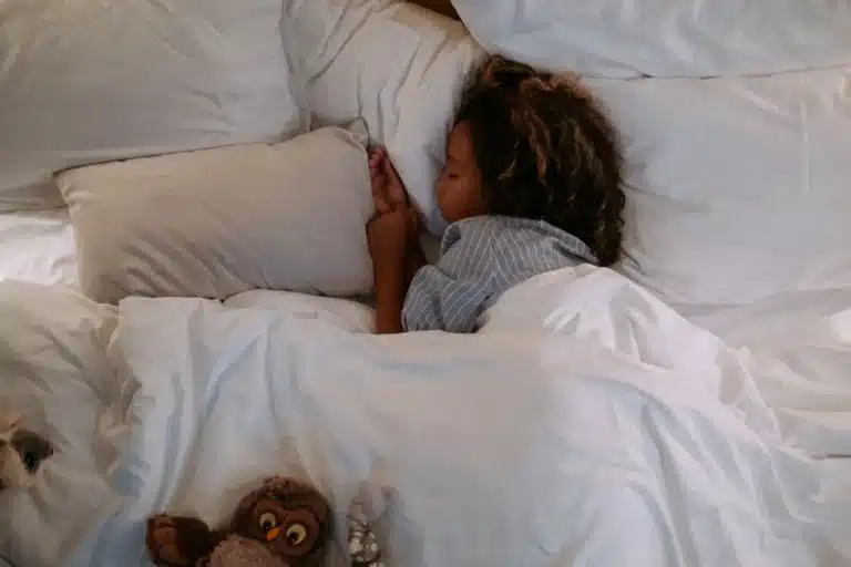 Enfant qui dort paisiblement dans un grand lit blanc
