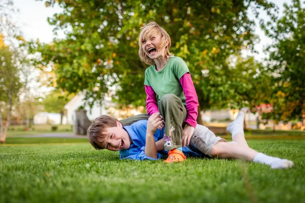 Deux enfants qui rient en jouant ensemble dans l’herbe