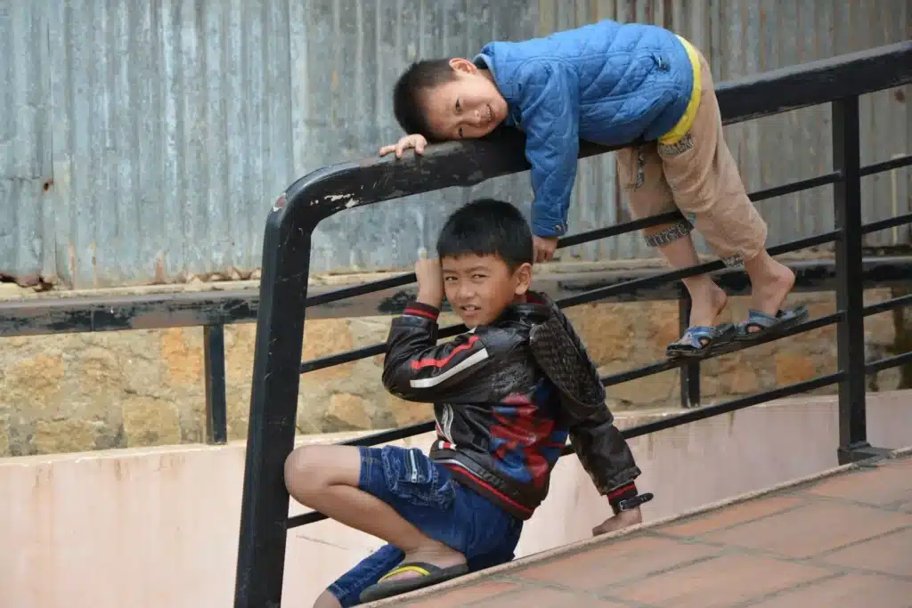 Deux garçons souriants qui grimpent ensemble sur une structure de jeux