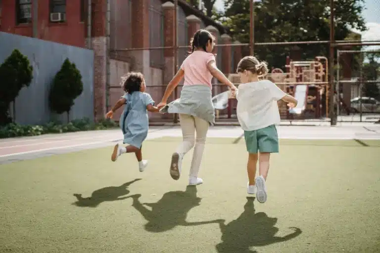 Trois enfants qui courent en se tenant la main dans une cour