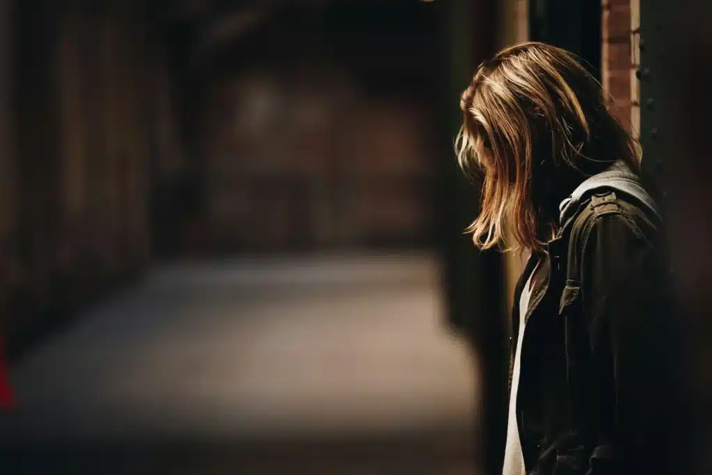 Femme de profil dans un couloir sombre, le visage caché par ses cheveux