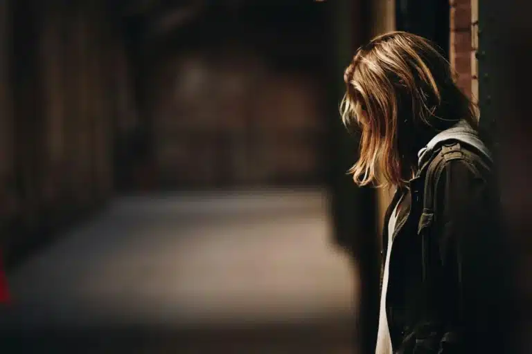 Femme de profil dans un couloir sombre, le visage caché par ses cheveux