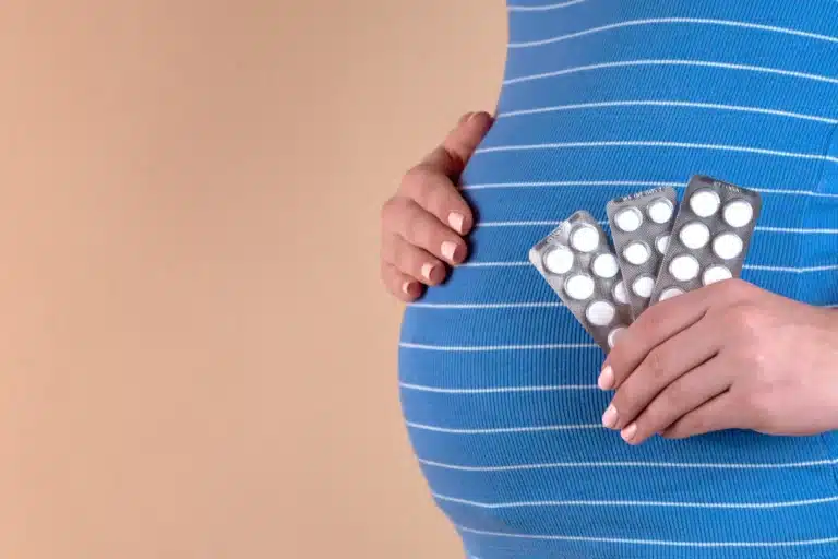 Femme enceinte tenant des plaquettes de comprimés contre son ventre