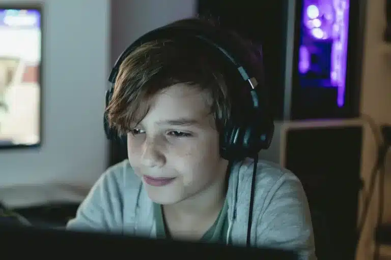 Garçon avec un casque audio, concentré sur un jeu à l'ordinateur