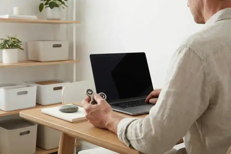 Homme à son bureau avec un ordinateur portable et un fidget spinner à la main