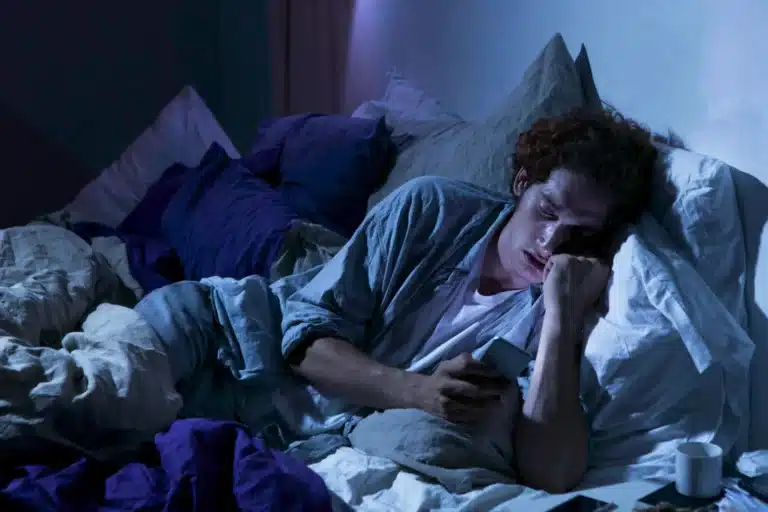 Homme éveillé la nuit dans son lit, son téléphone à la main