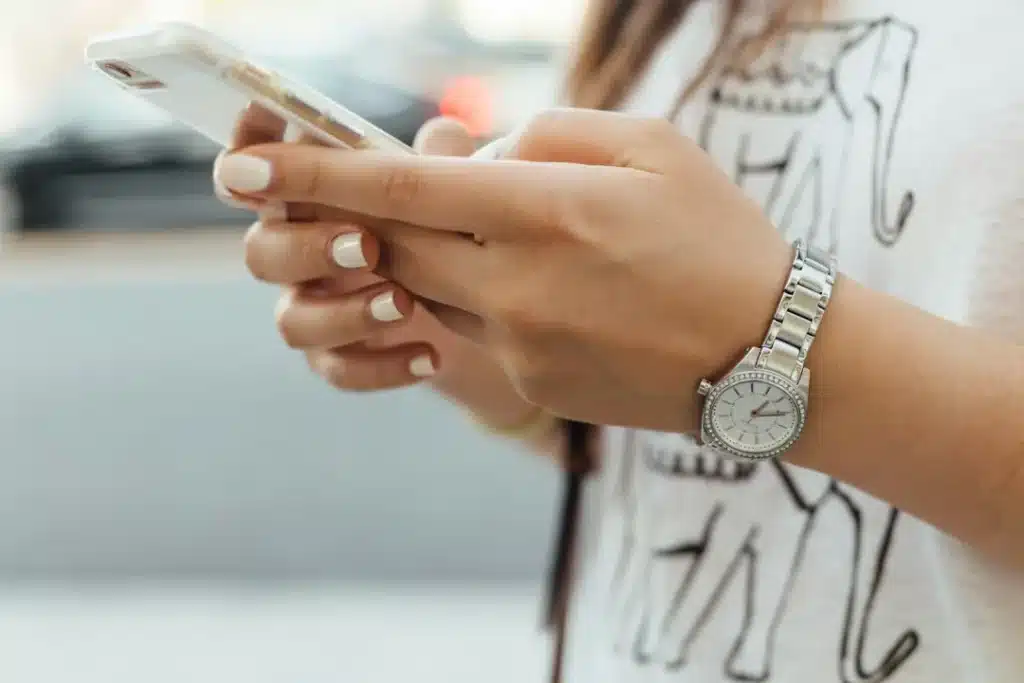 Femme qui tient son téléphone à la main, en pleine journée