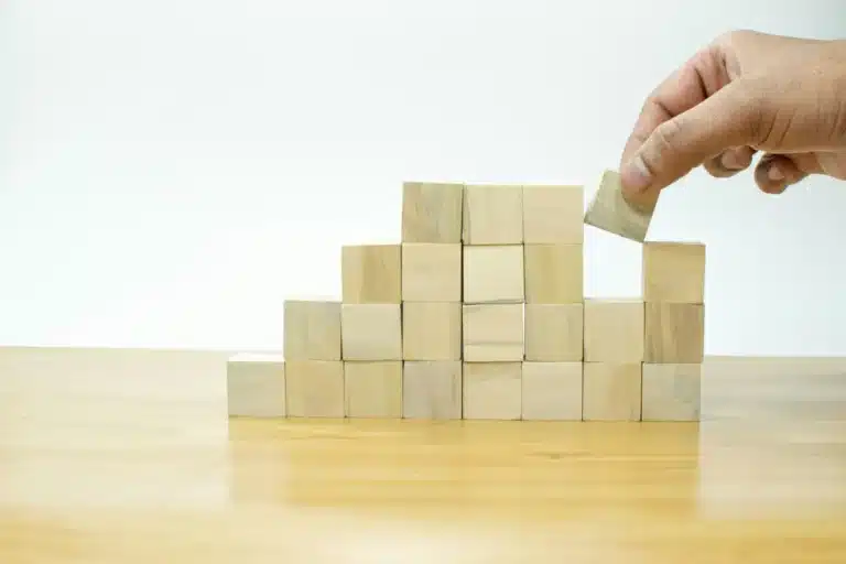 Main qui empile des blocs de bois, une étape après l'autre