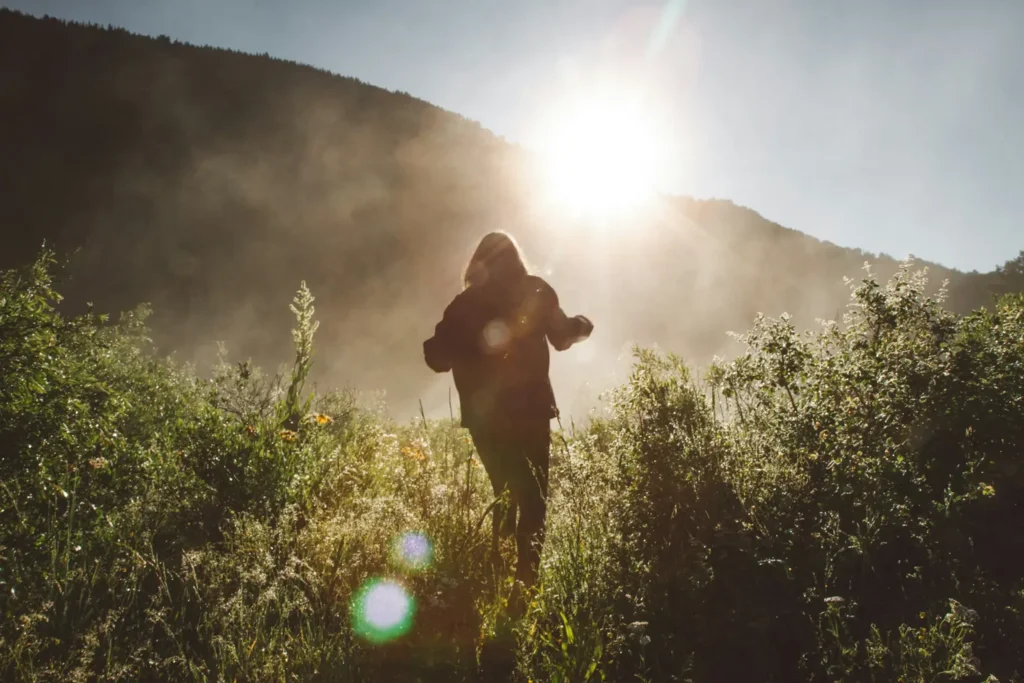 Personne qui marche dans un champ baigné de lumière au lever du soleil