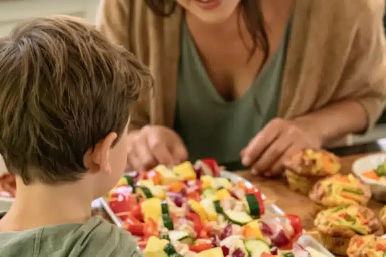 Mère et fils qui préparent des brochettes de légumes