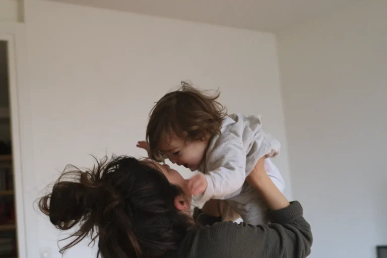 Mère qui soulève son bambin à bout de bras dans le salon