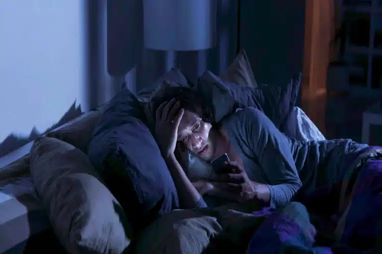 Personne éveillée tard dans son lit, éclairée par son téléphone