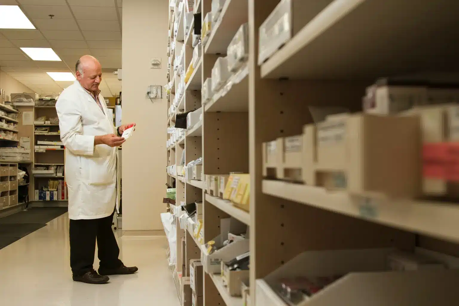 Pharmacien qui lit une boîte de médicament entre les rayons