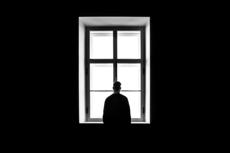 Silhouette d'une personne seule devant une fenêtre lumineuse