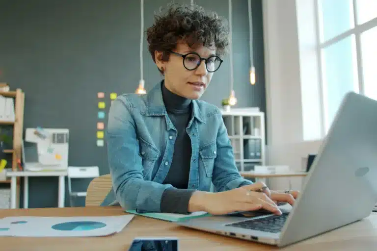Femme concentrée qui travaille sur son ordinateur portable dans un bureau lumineux